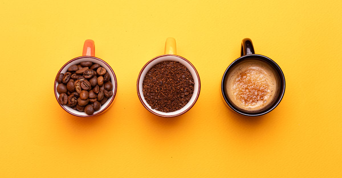 Three stages of coffee displayed on cups resting on a vibrant yellow surface.
